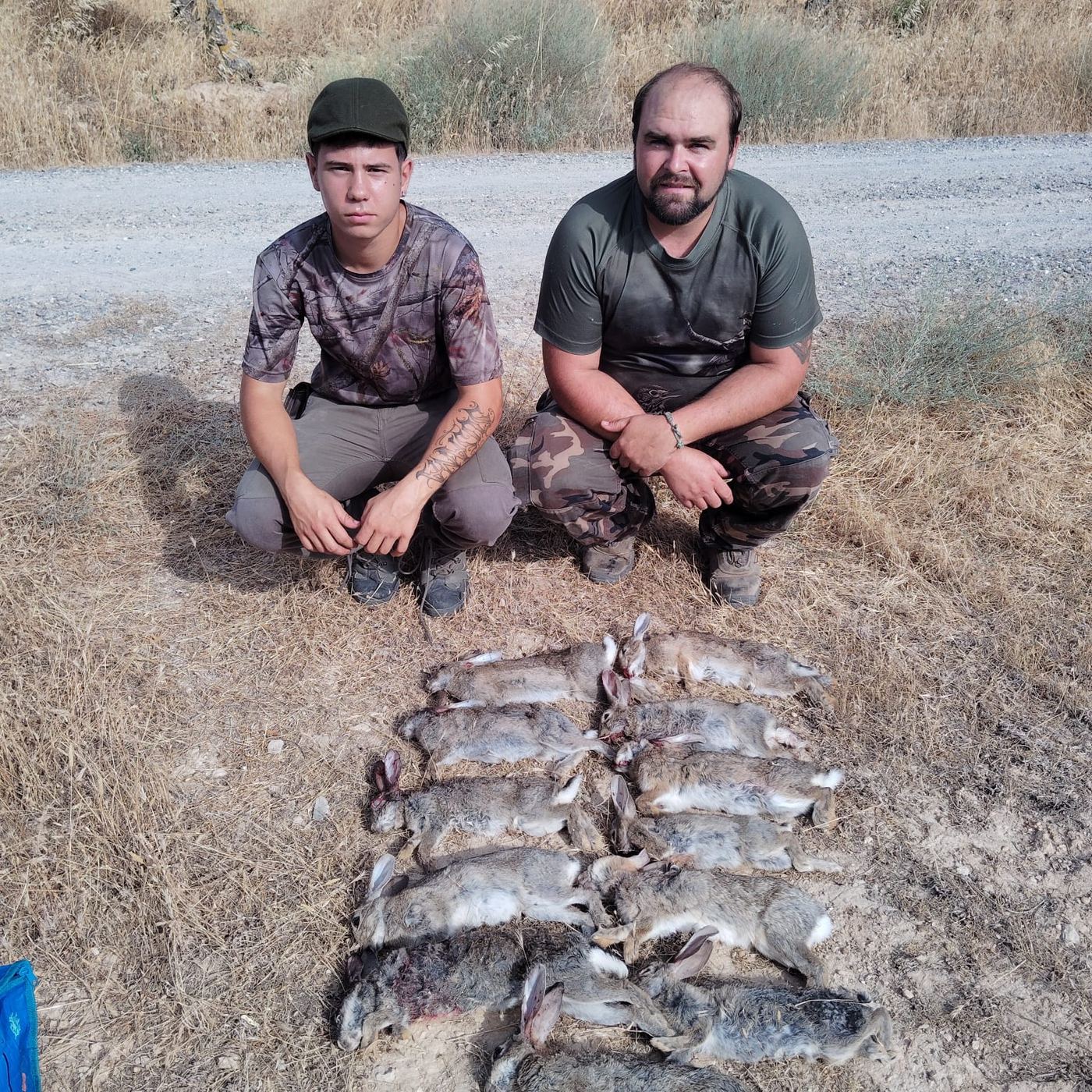 Dos cazadores con la percha de conejos del día